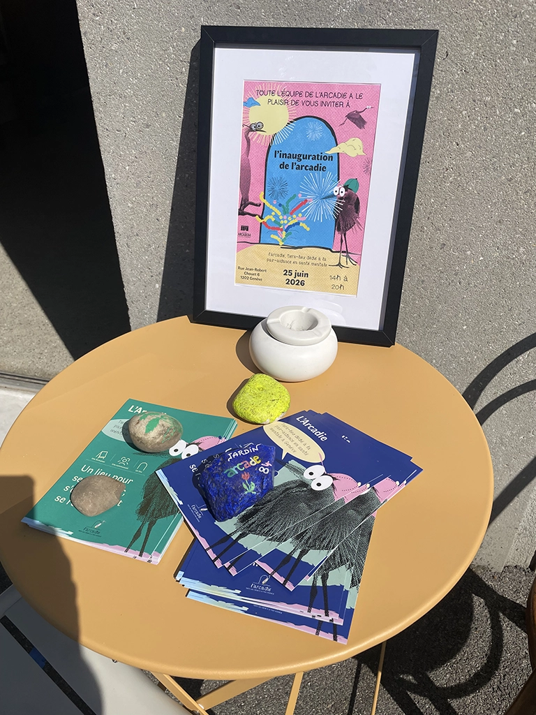 table basse ronde extérieure avec des flyers et l’affiche pour l’inauguration de l’Arcadie