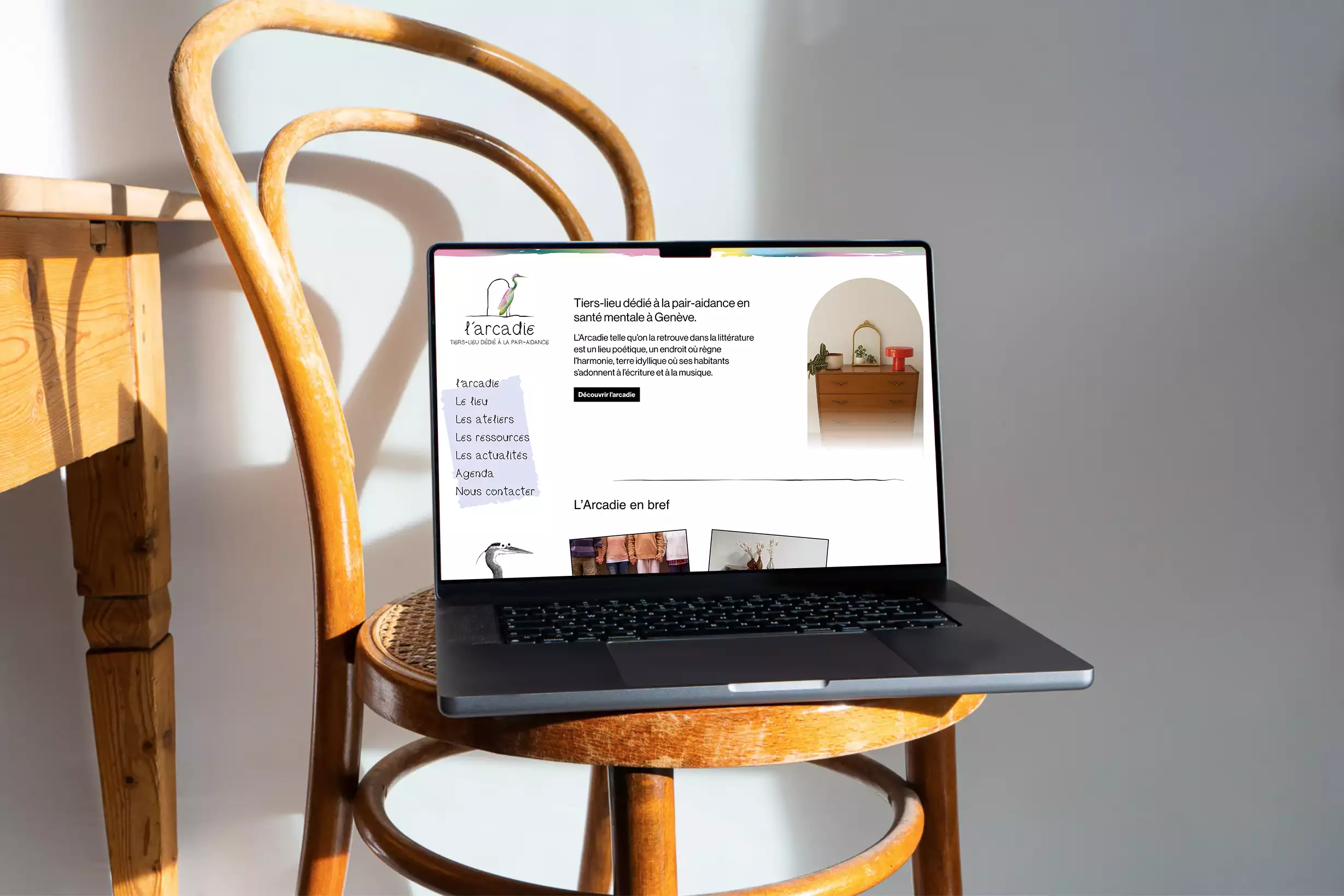 visuel repésentant un ordinateur portable avec la page d’accueil du site de l’Arcadie posé sur une chaise de style vintage